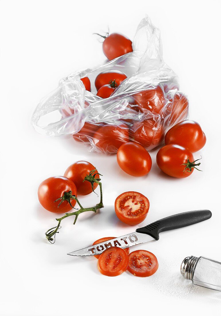 Tomatoes in a plastic bag with a knife and a salt shaker