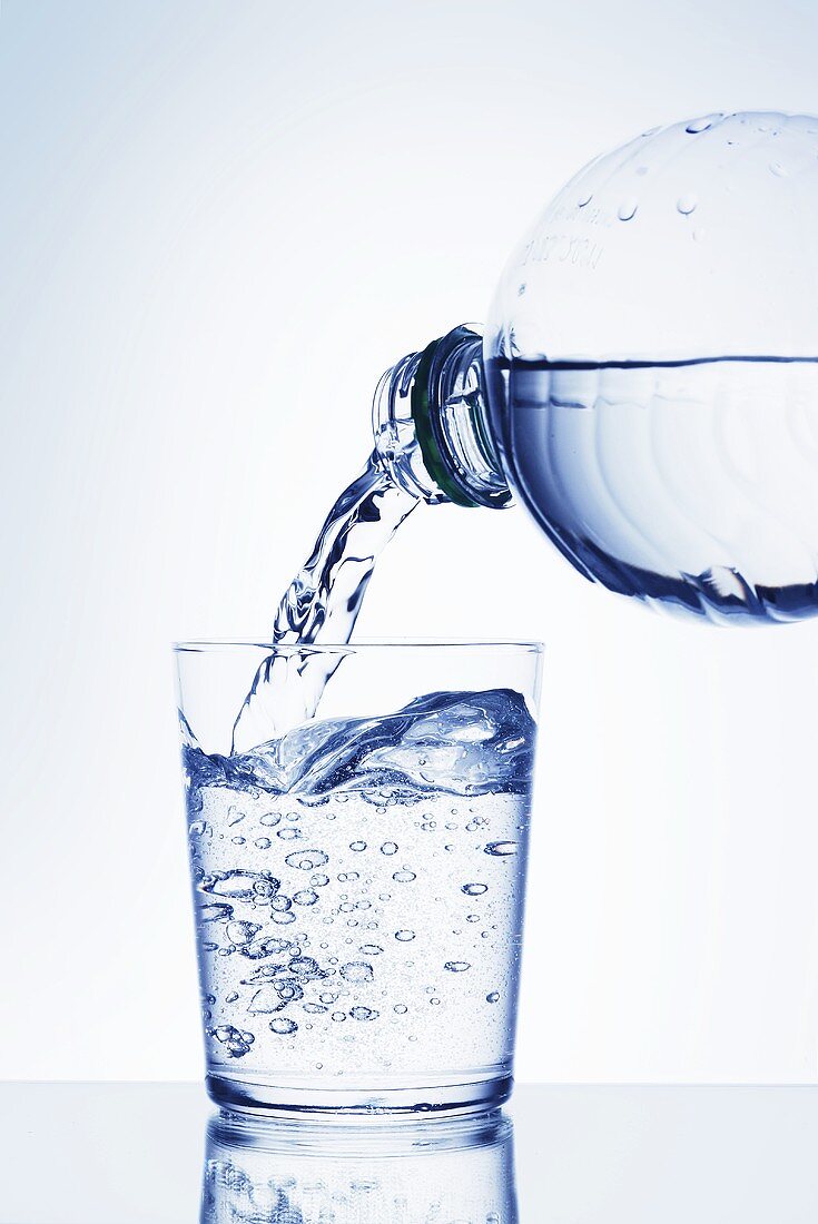 Wasser aus Plastikflasche in Glas gießen