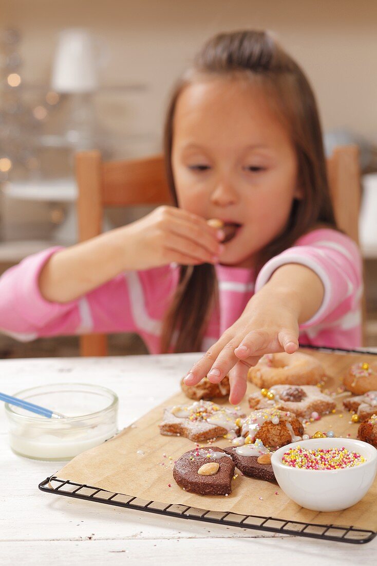 Mädchen nascht frisch gebackene Weihnachtsplätzchen