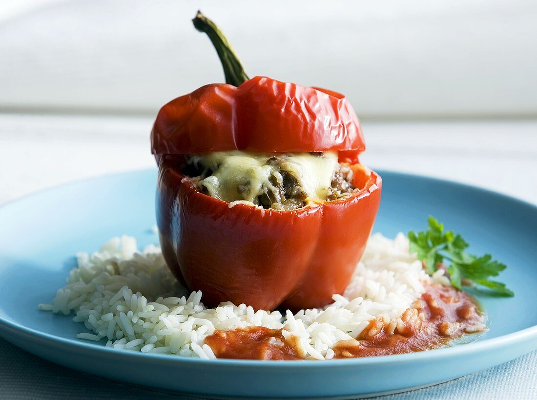 A pepper stuffed with minced meat and cheese on a bed of rice