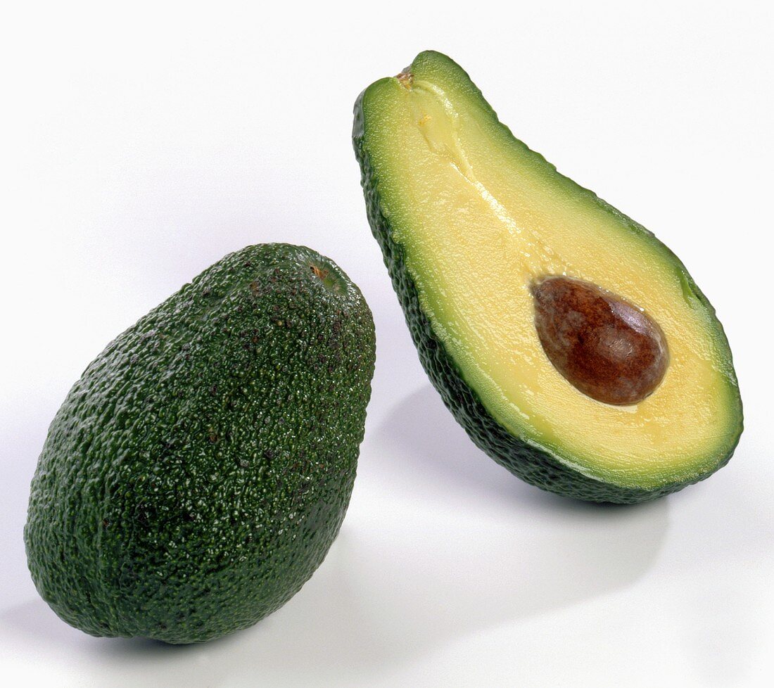 One whole avocado beside an avocado half