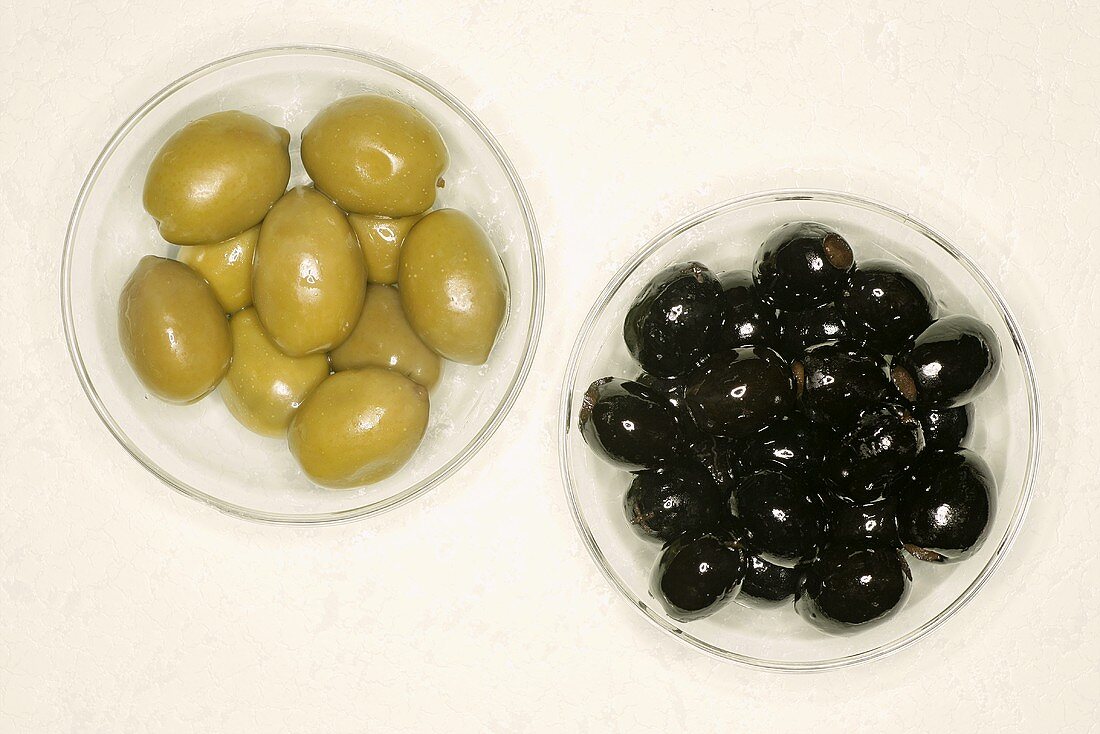 Schwarze und grüne Oliven in Glasschälchen