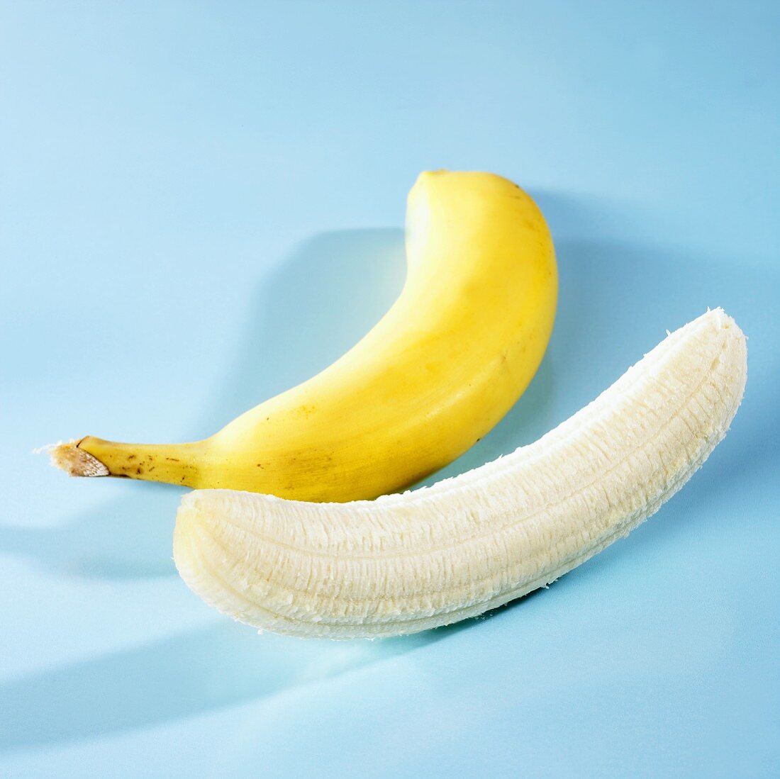 Eine geschlossene und eine geschälte Banane