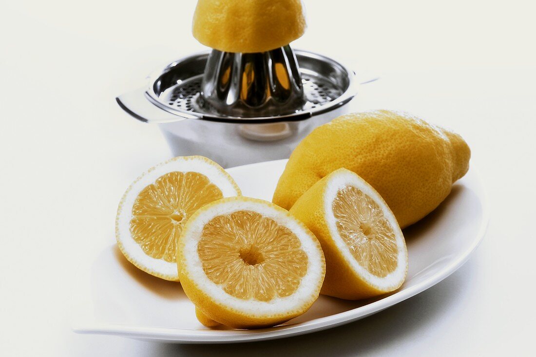 Zitronenhälften, dahinter Zitruspresse