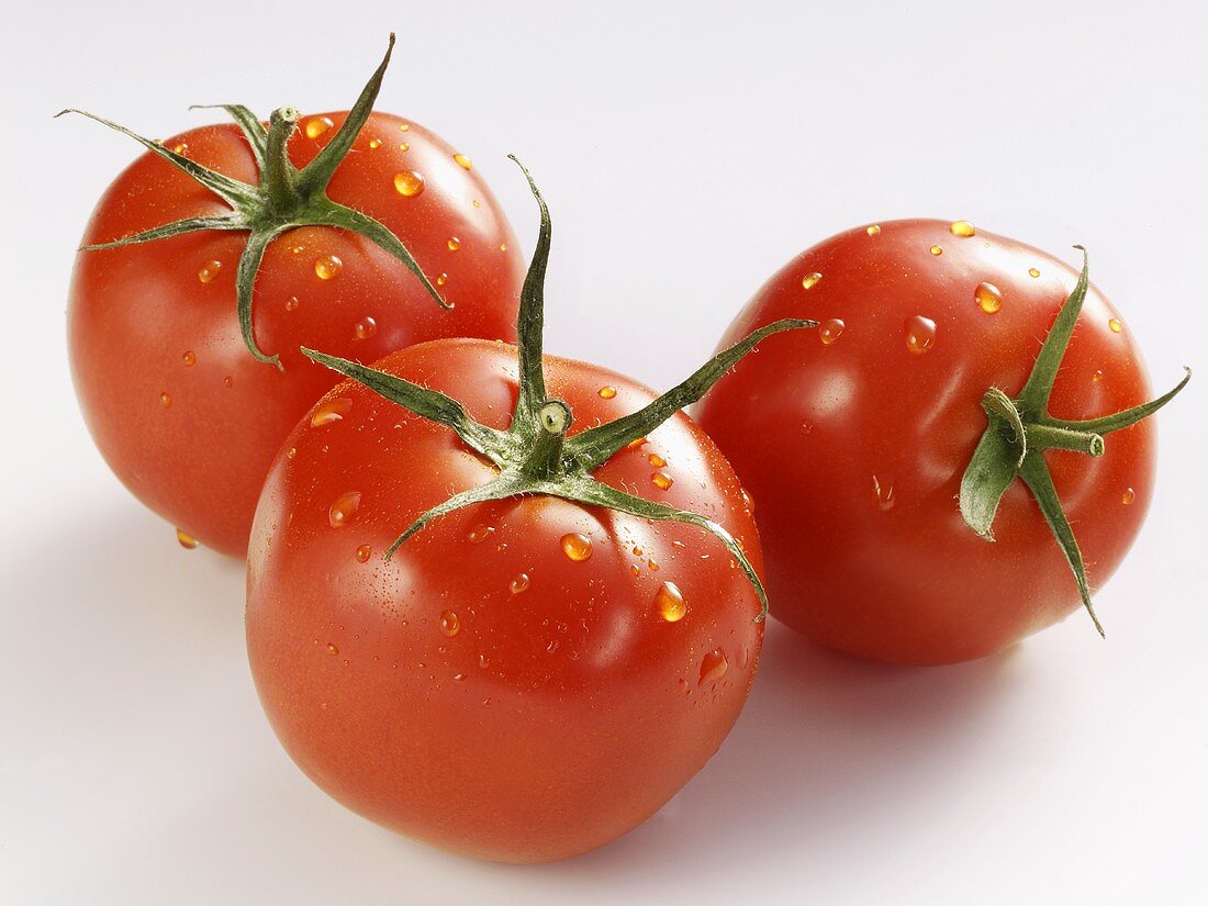 Three tomatoes with drops of water