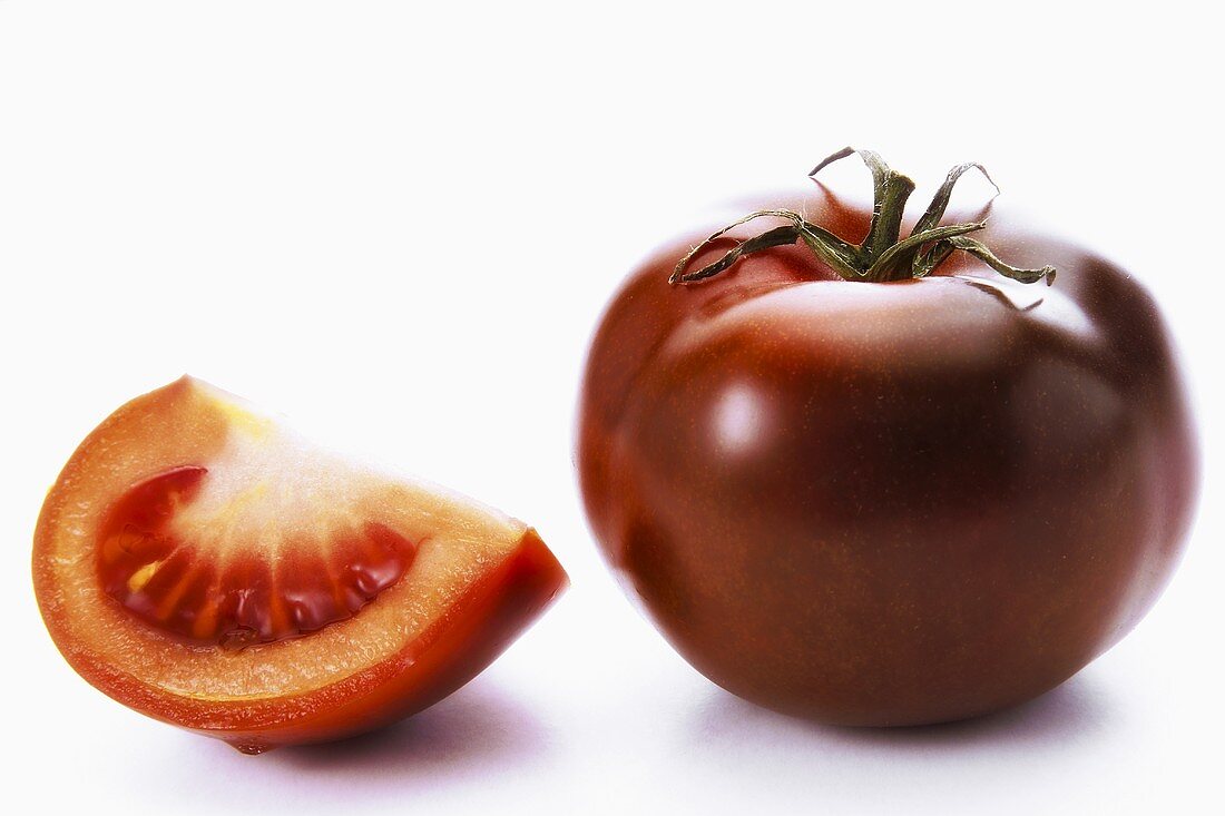 Eine ganze Tomate und ein Tomatenschnitz der Sorte 'Kumato'