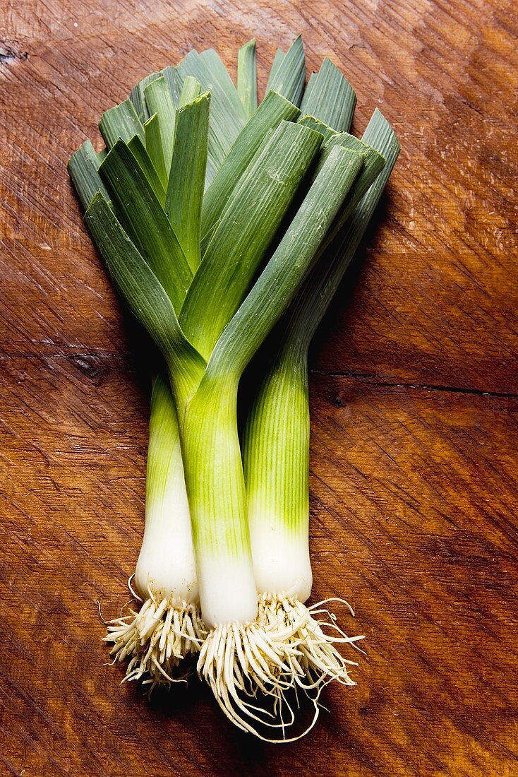 Three leeks on wooden background