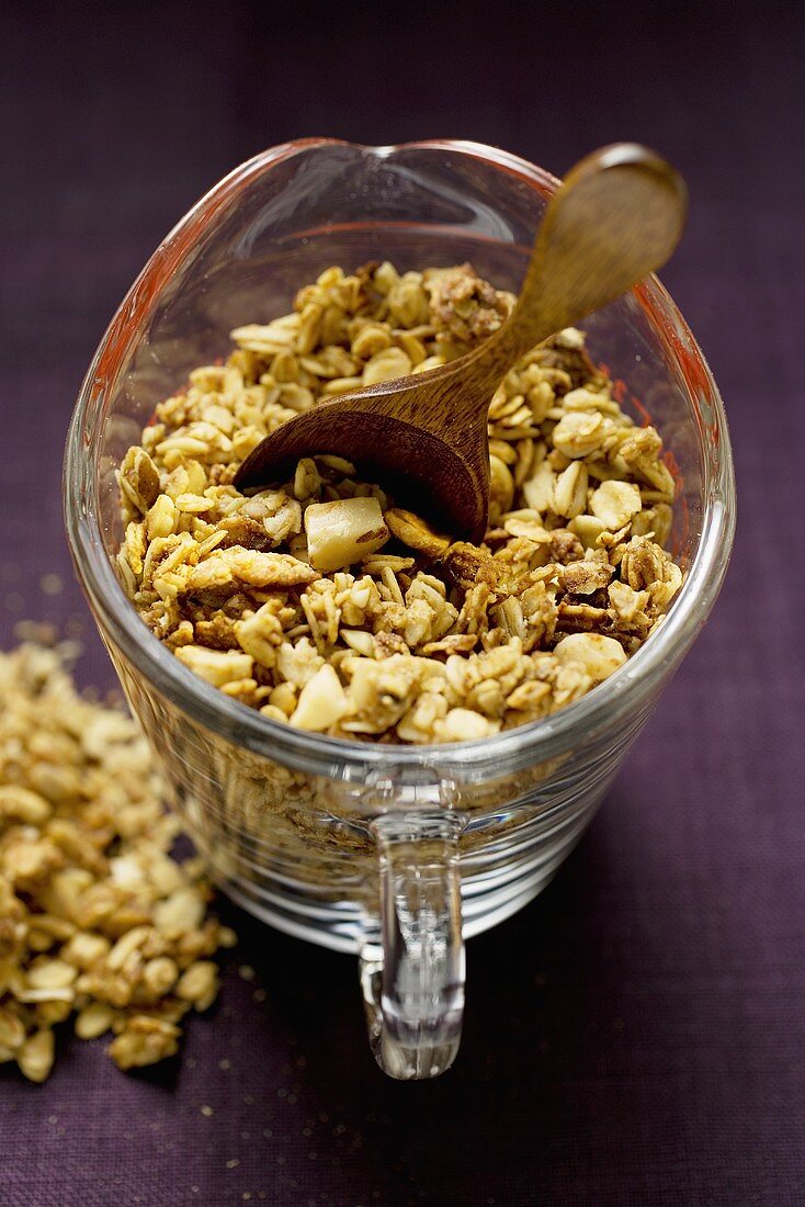 Crunchy muesli with wooden spoon in a measuring jug