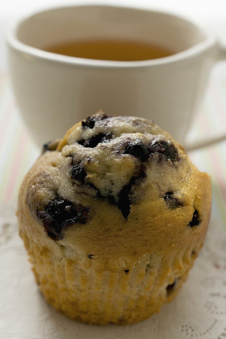 Blaubeermuffin vor einer Tasse Tee