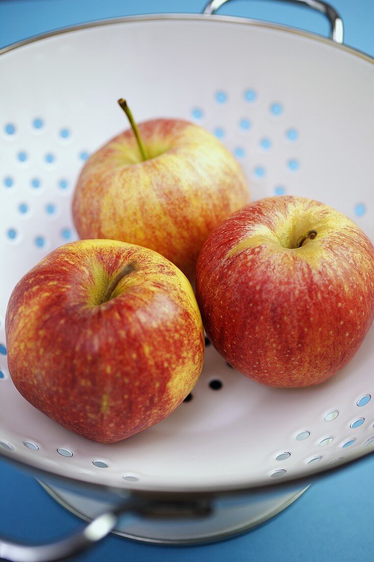 Drei Äpfel liegen in einem Sieb