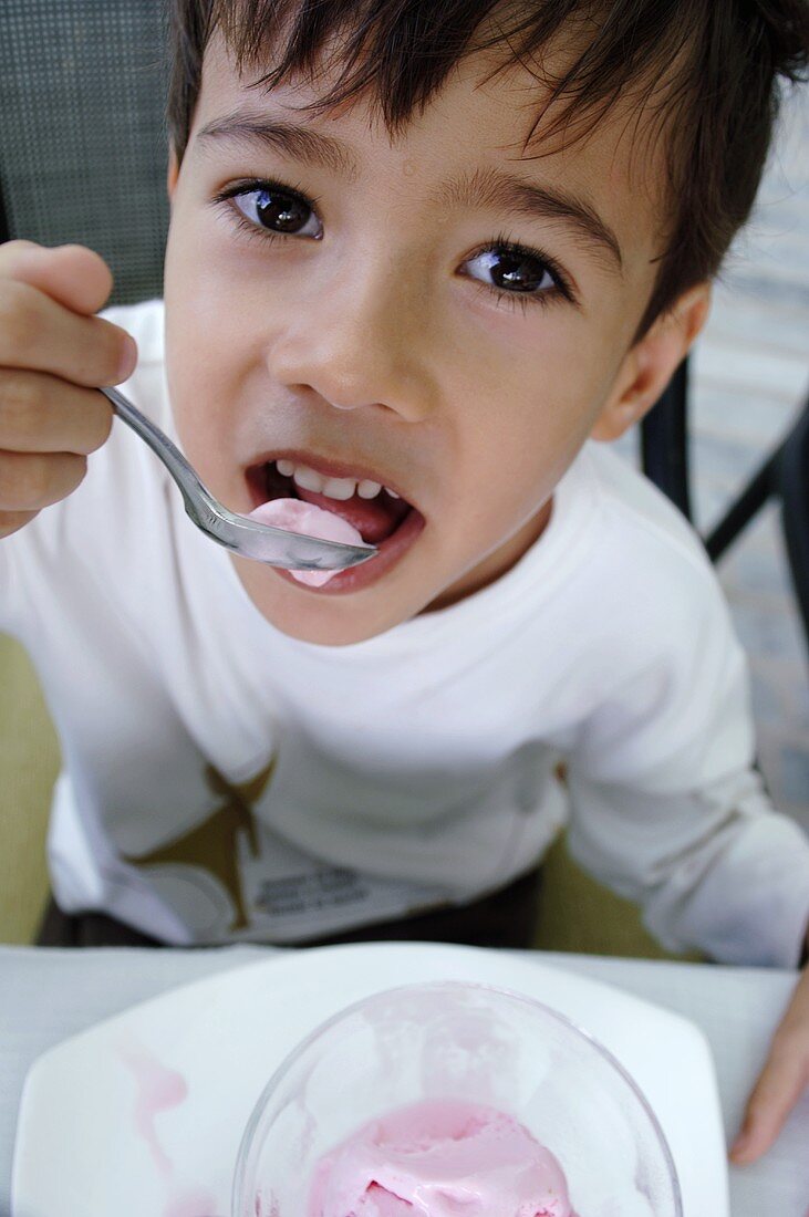 Small boy eating strawberry quark