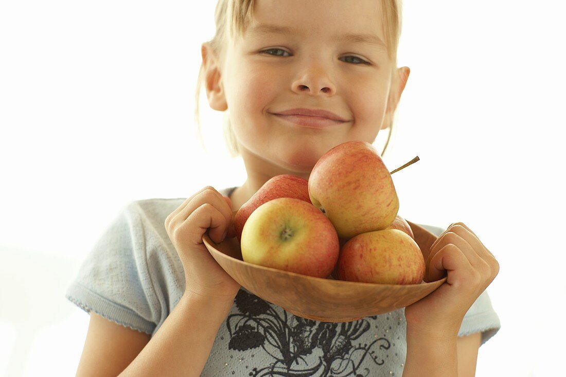 Kleines Mädchen hält eine Schale mit Äpfel