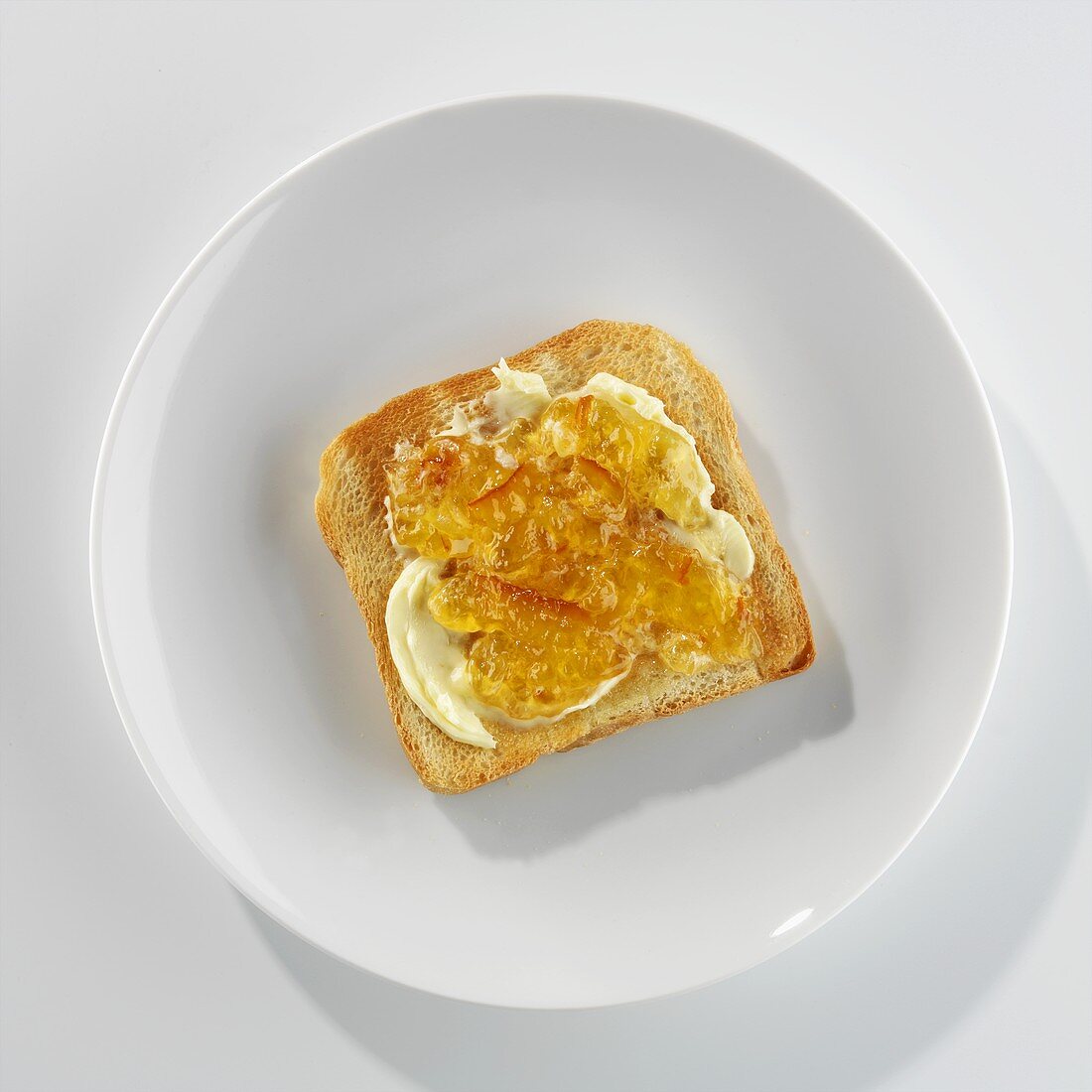 Eine Scheibe Toast mit Butter und Marmelade auf einem Teller