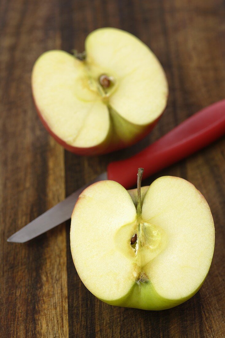 A halved apple with knife