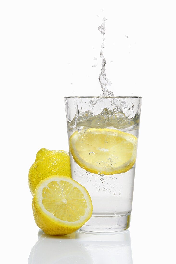 A slice of lemon falling into a glass of water