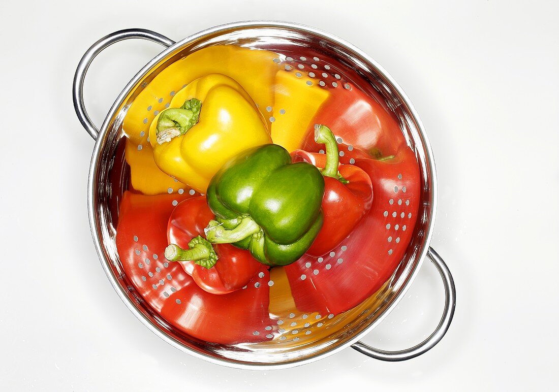Four peppers (red, yellow, green) in a colander