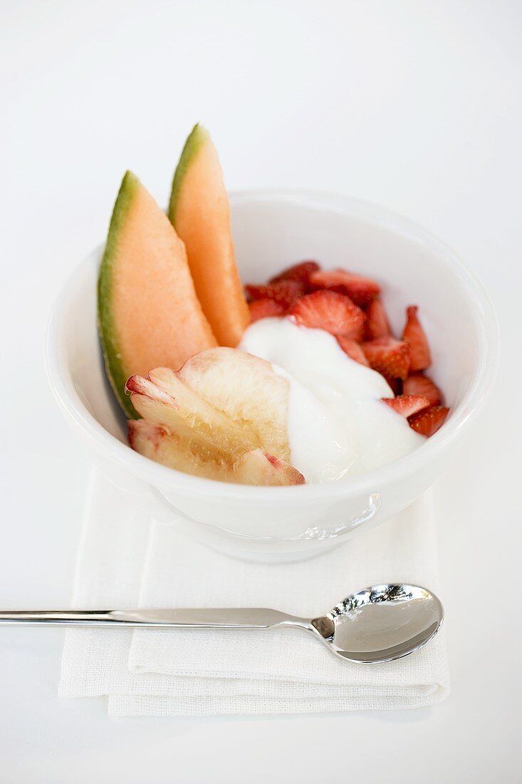 Obstsalat von Pfirsich, Melone und Erdbeere mit Joghurt
