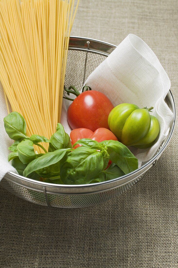 Tomaten, Spaghetti und Basilikum in einem Sieb