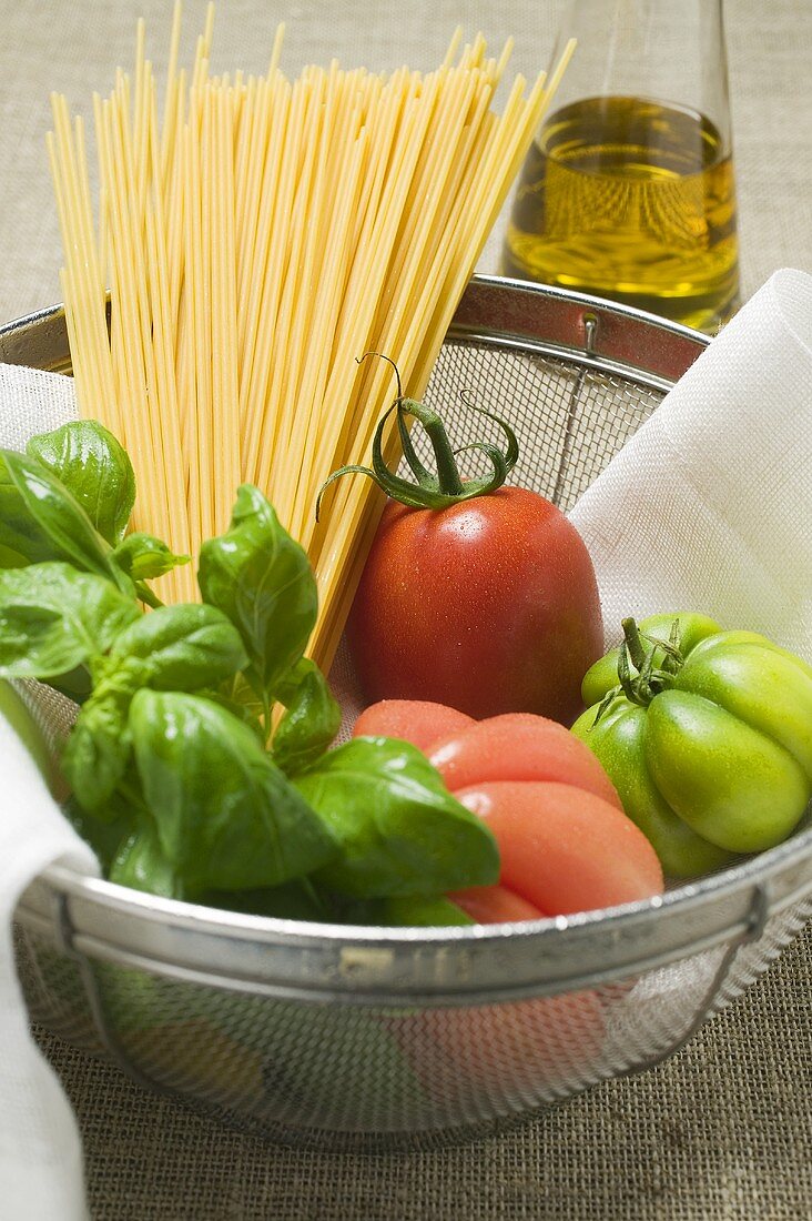 Tomatoes, spaghetti and basil in a bowl