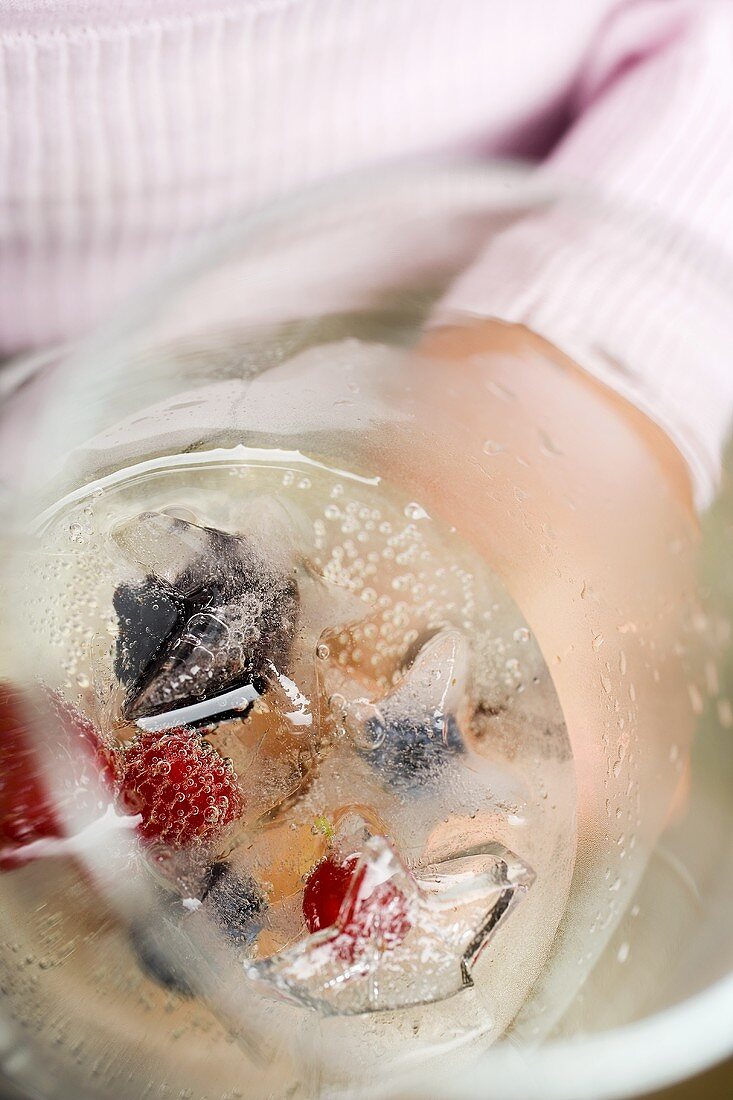 A glass of champagne with berry ice cubes