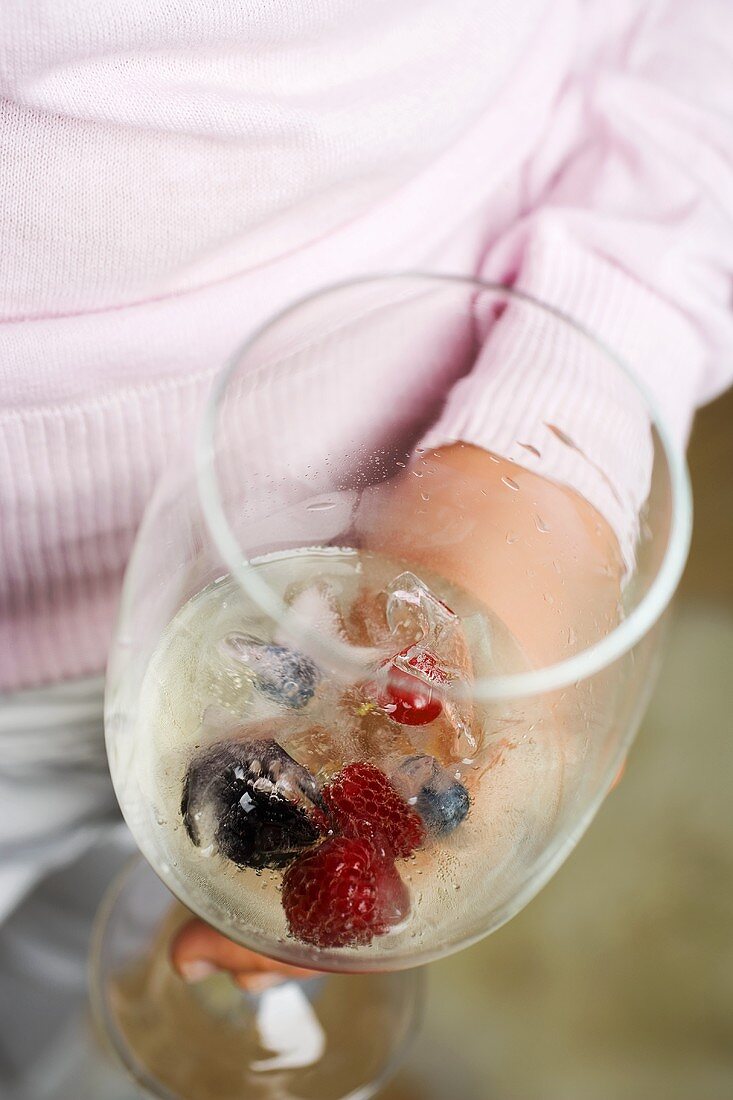 A glass of champagne with berry ice cubes