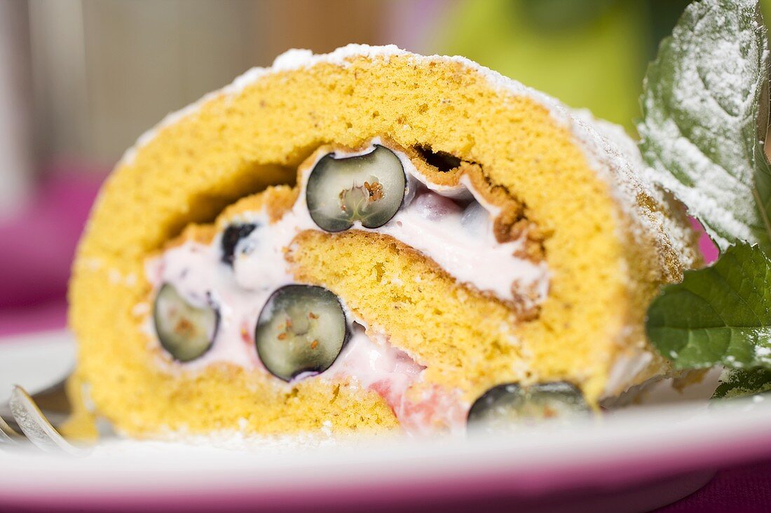 Ein Stück Biskuitroulade mit Beeren-Quark-Füllung