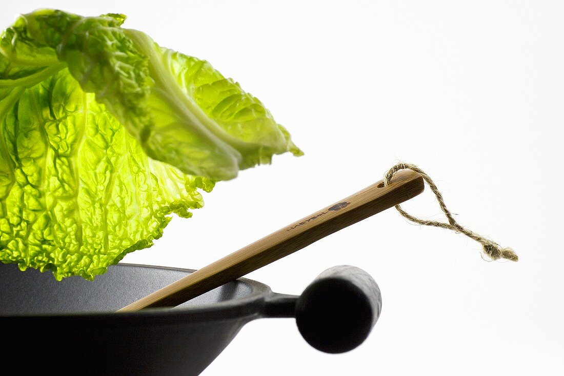 Savoy cabbage leaf falling into a wok