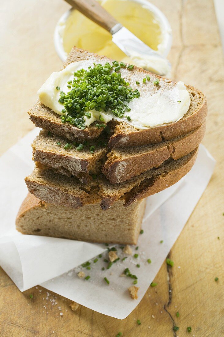 Several slices of bread in a pile with butter and chives