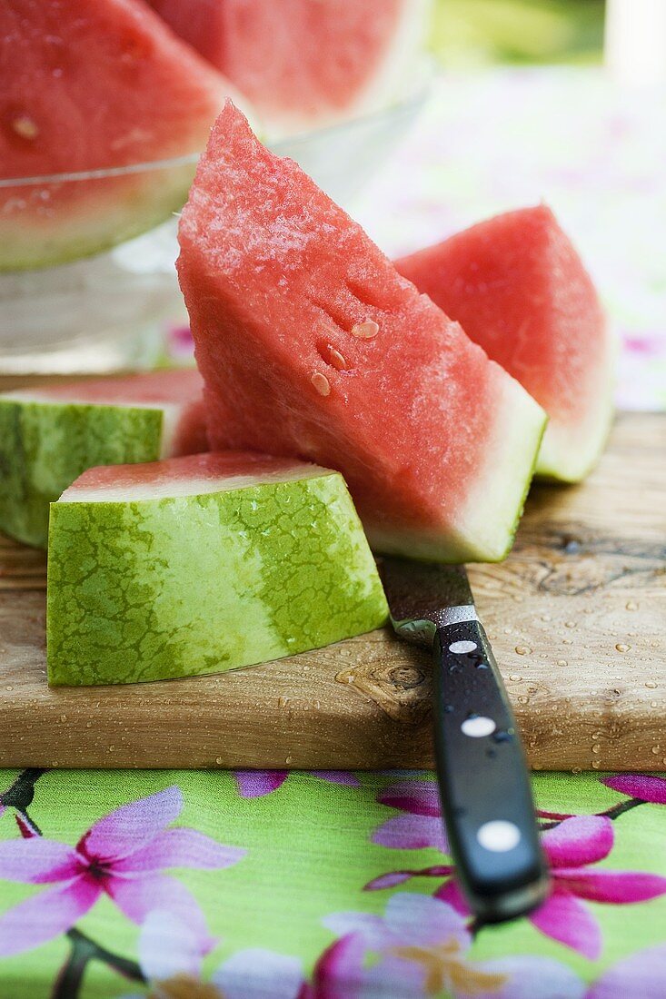 Watermelon, cut into pieces, on a wooden board
