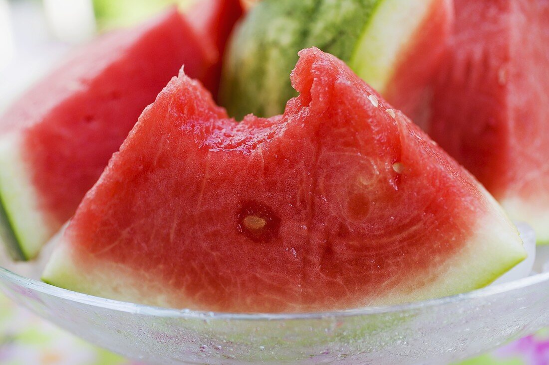 Wedge of watermelon, a bite taken, in a glass bowl