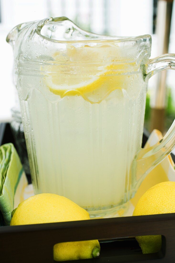 Lemonade in a glass jug with slices of lemon