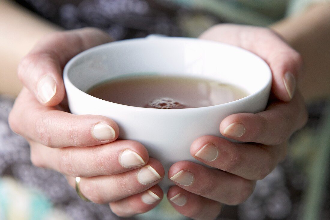 Zwei Hände halten eine Tasse Tee