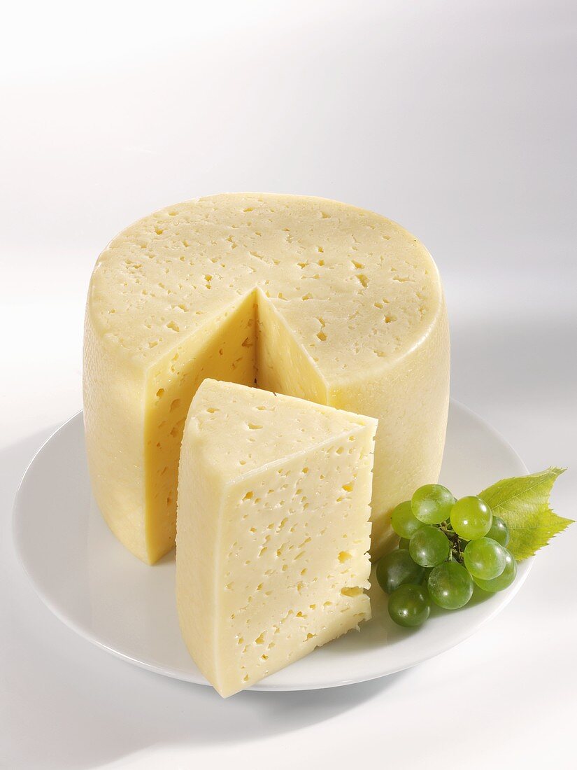 Angeschnittener Tilsiter Käse mit Trauben
