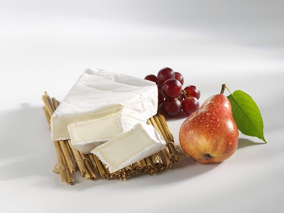 Brie, partly sliced, with grapes and pear