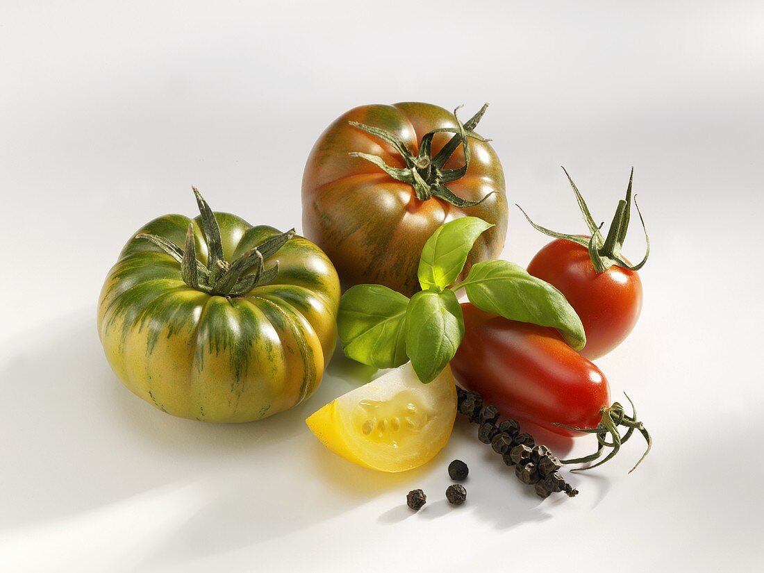 Various types of tomatoes with basil and bunch of pepper