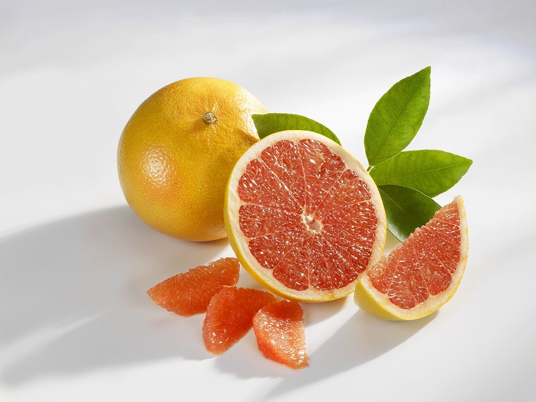 One whole and one half grapefruit with segments and wedge