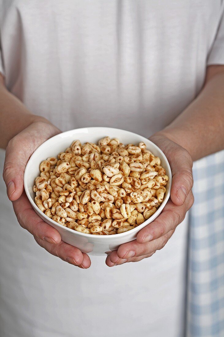 Hände halten Schale mit Frühstückscerealien