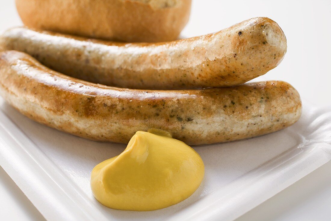Two sausages with mustard and bread roll