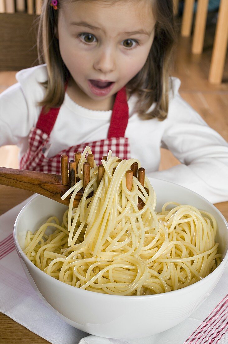 Kleines Mädchen sitzt vor eine Schüssel gekochter Spaghetti