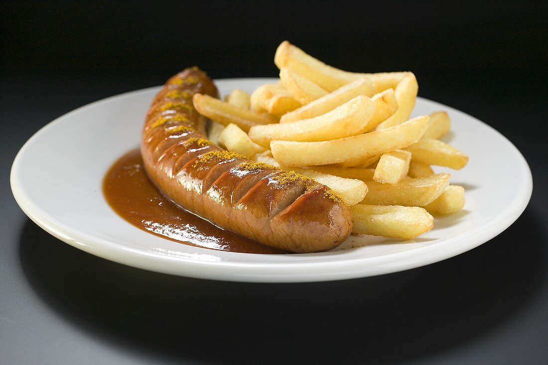 Currywurst mit Pommes & Ketchup auf einem Teller