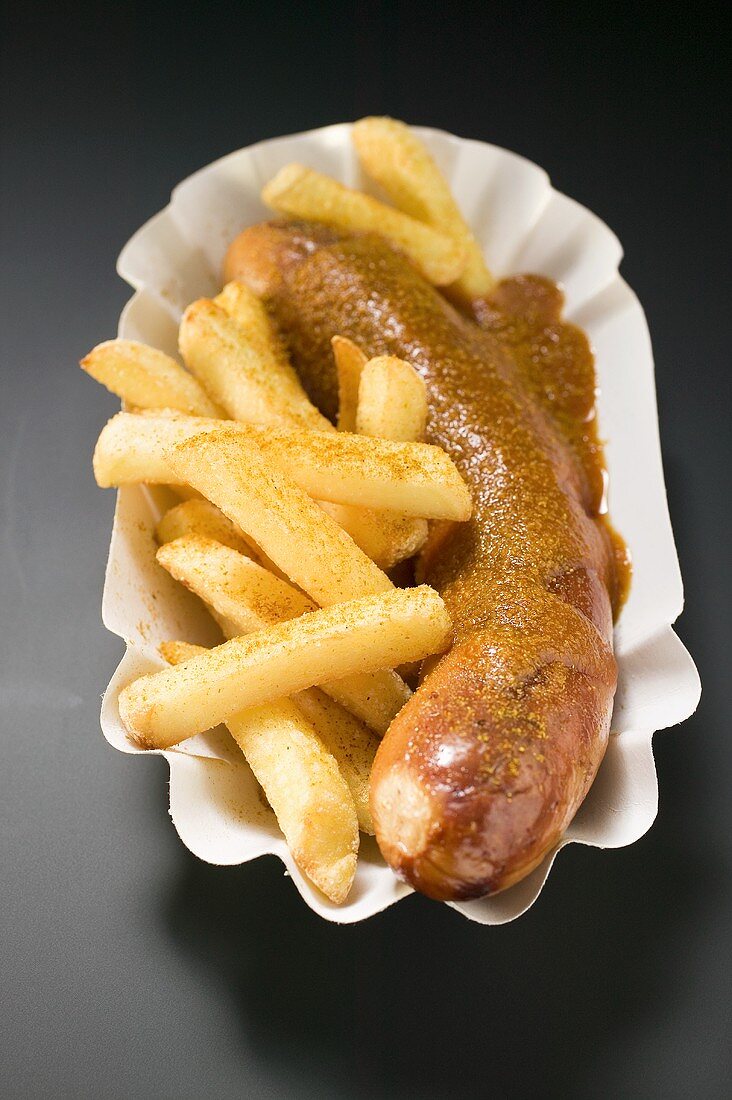 Currywurst with chips in paper dish