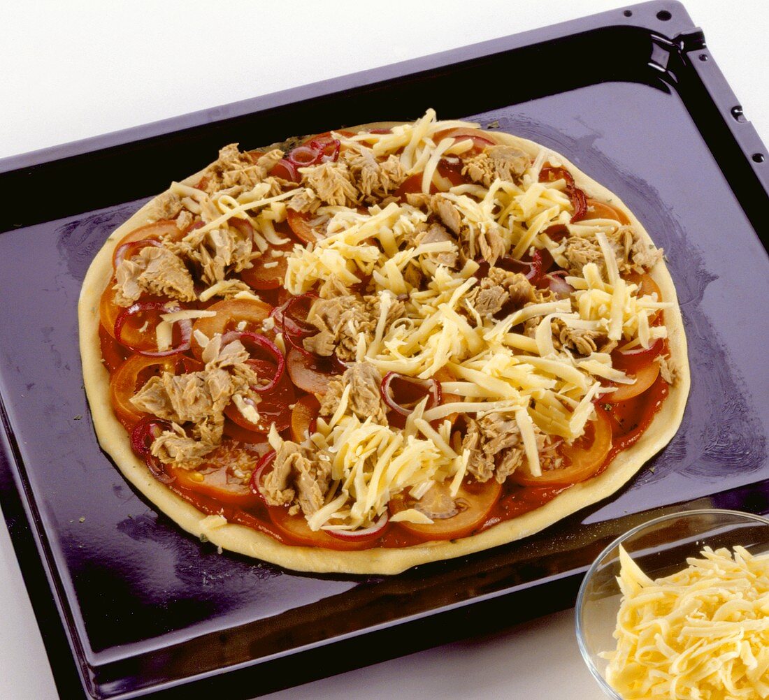 Unbaked tuna pizza on baking tray