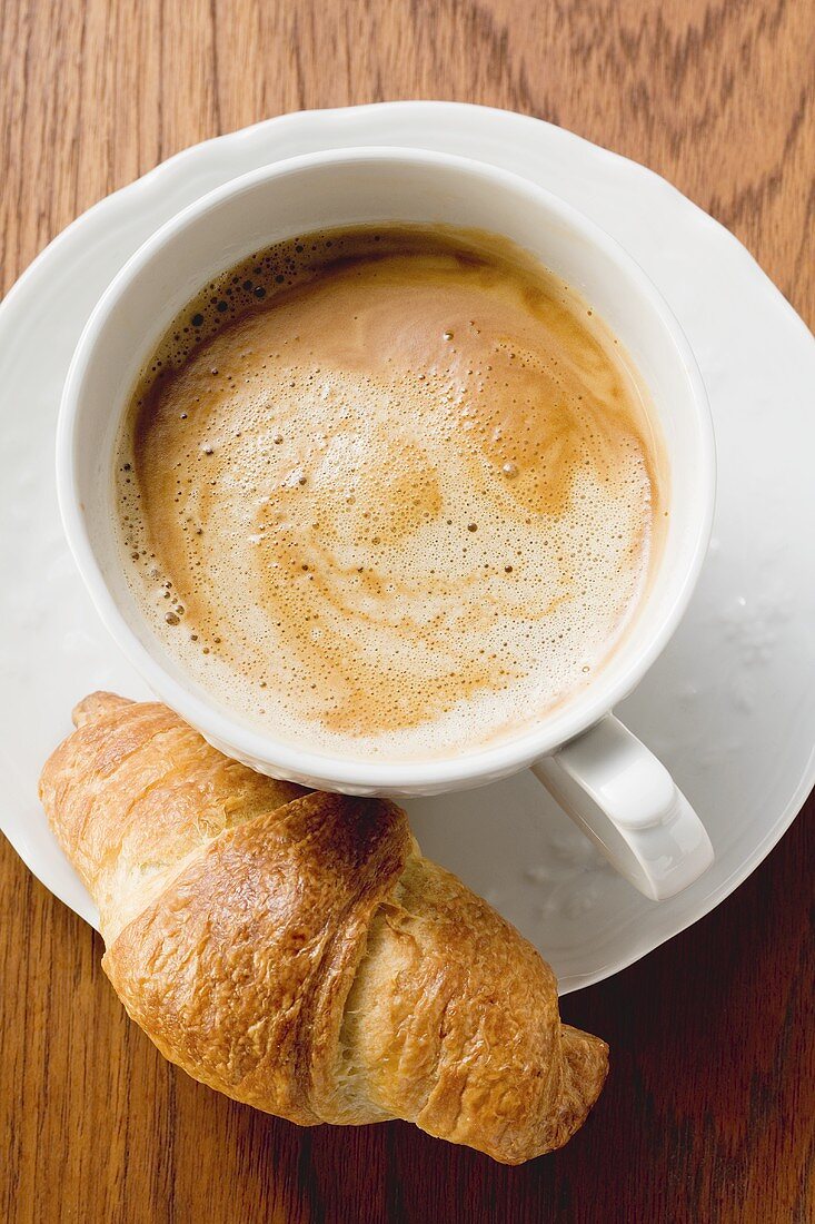 Eine Tasse Cappuccino mit Croissant