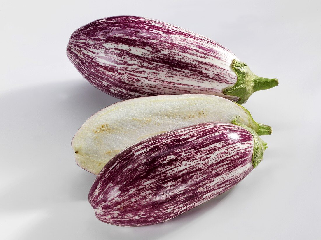 Two striped aubergines, one halved