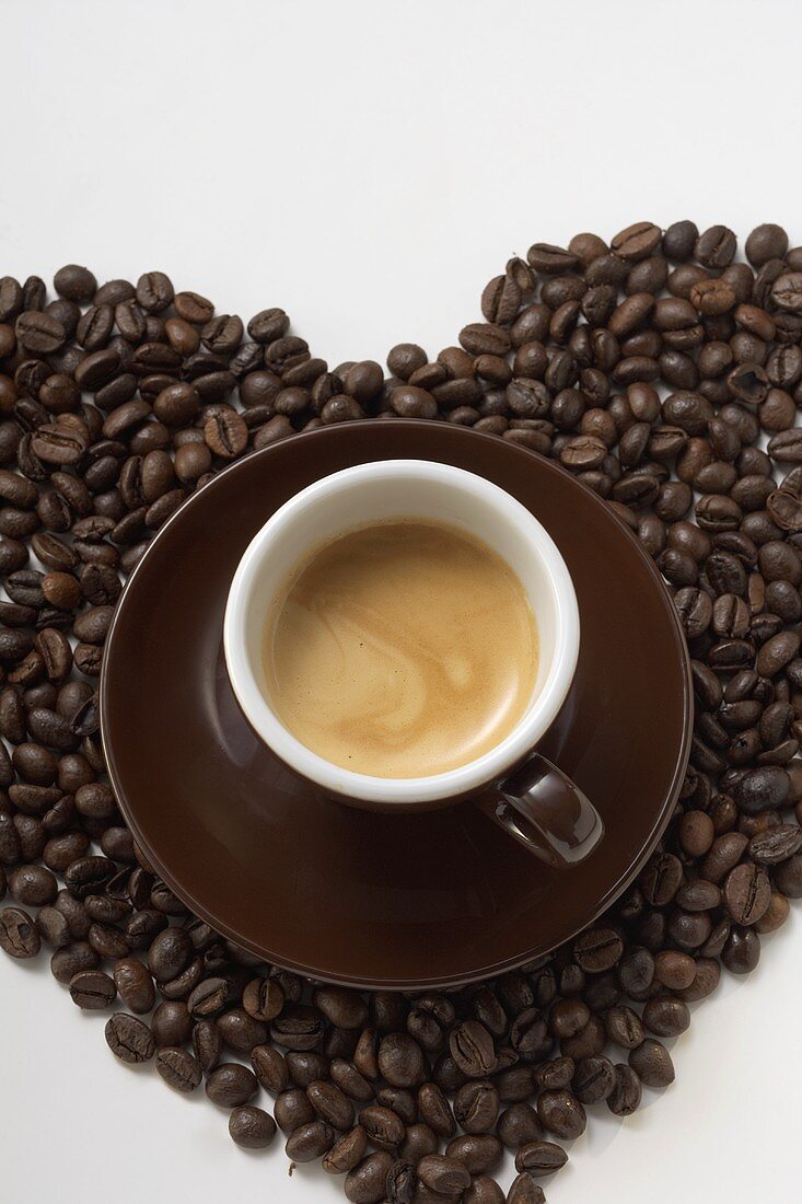 A cup of coffee on a heart of coffee beans