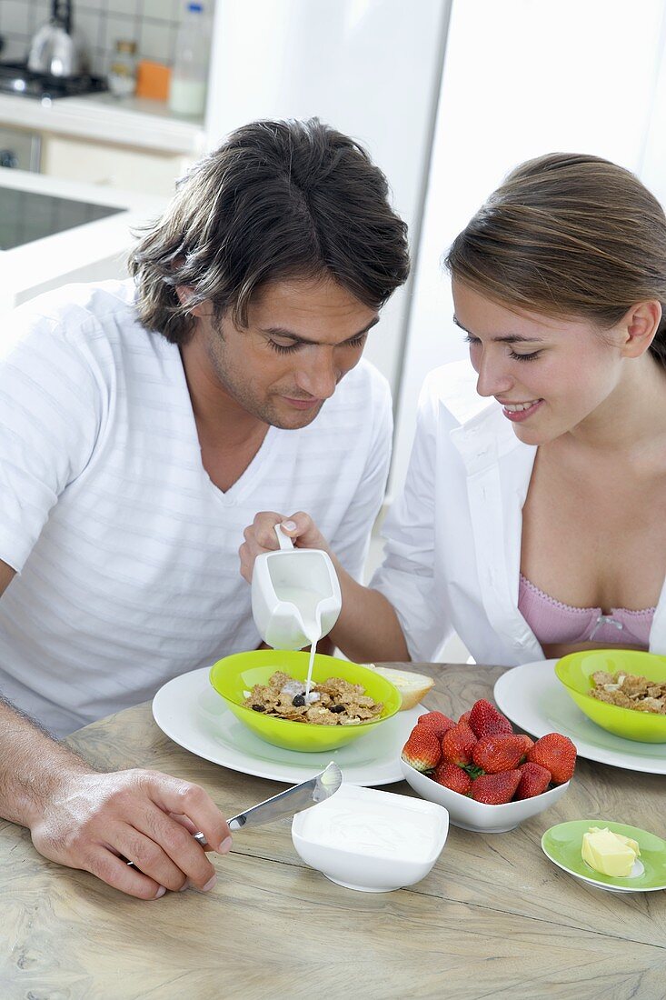 Woman pouring milk onto man's muesli