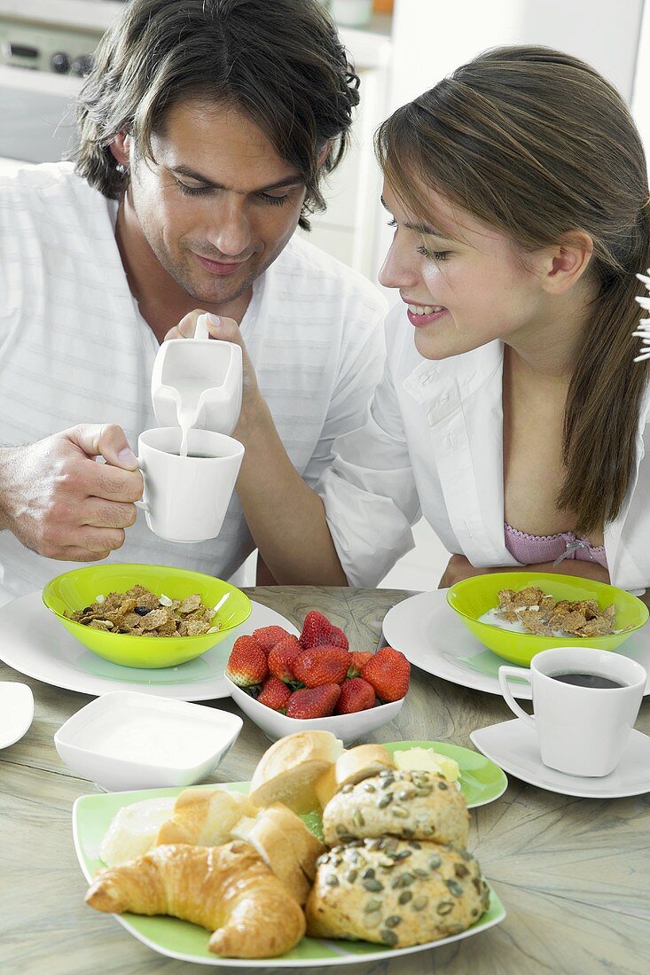 Woman putting milk into man's coffee