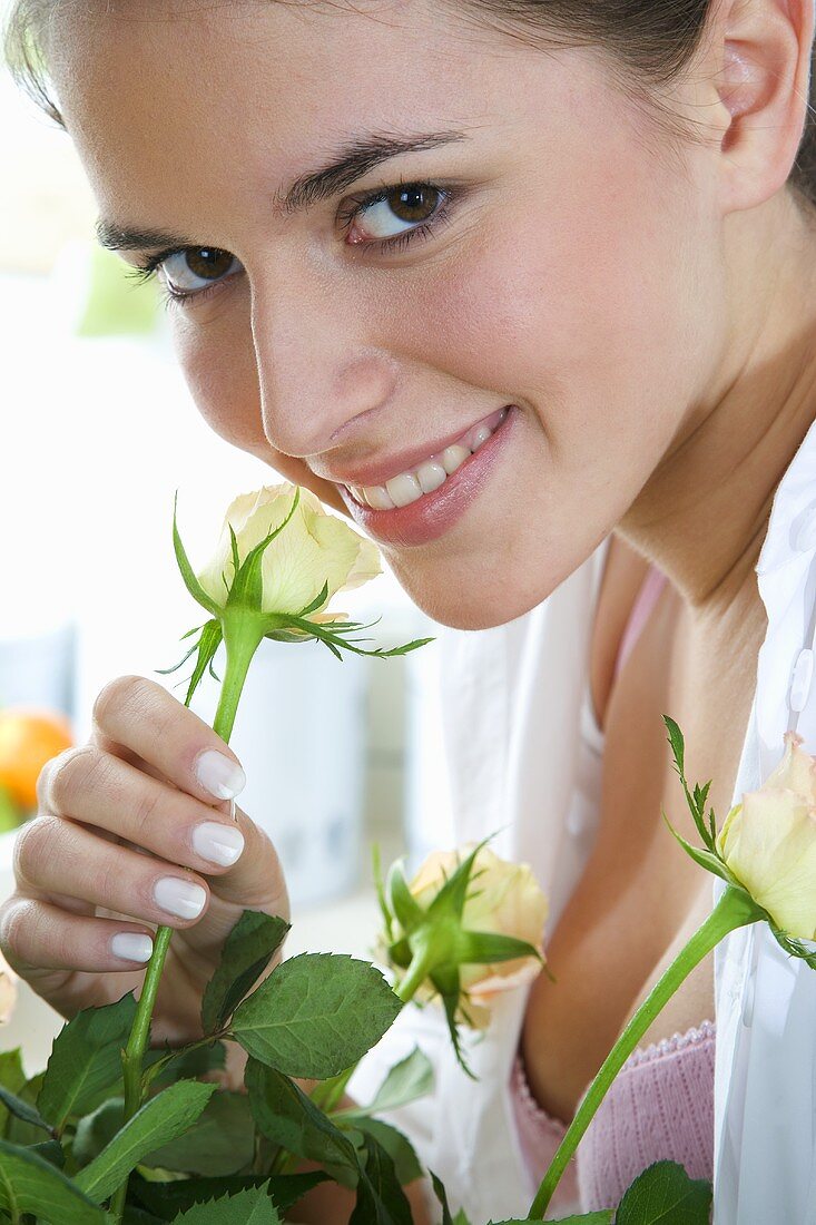 Junge Frau riecht an einer Rosenblüte