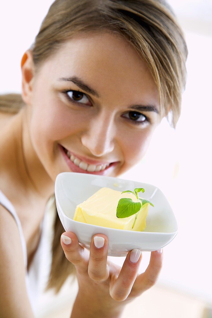 Junge Frau hält ein Schälchen mit Butter in der Hand