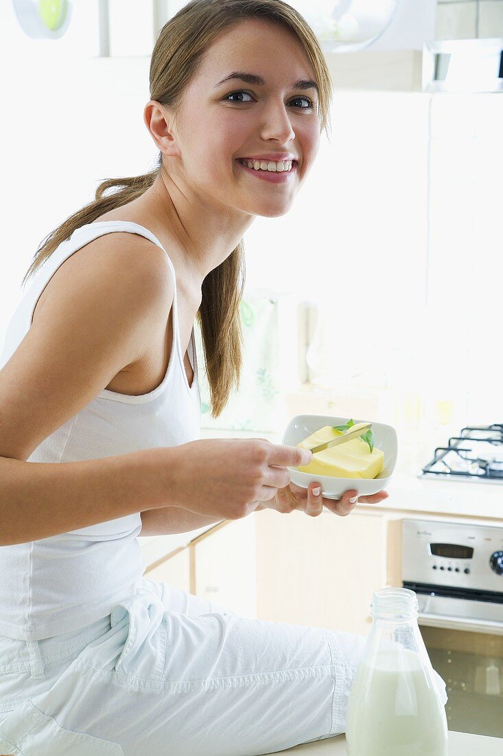 Young woman holding a small dish of butter and a knife